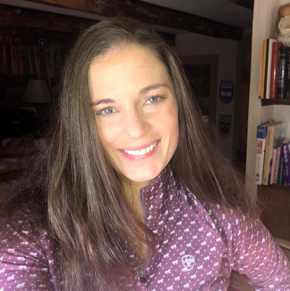 A woman is smiling for the camera while wearing a purple shirt.