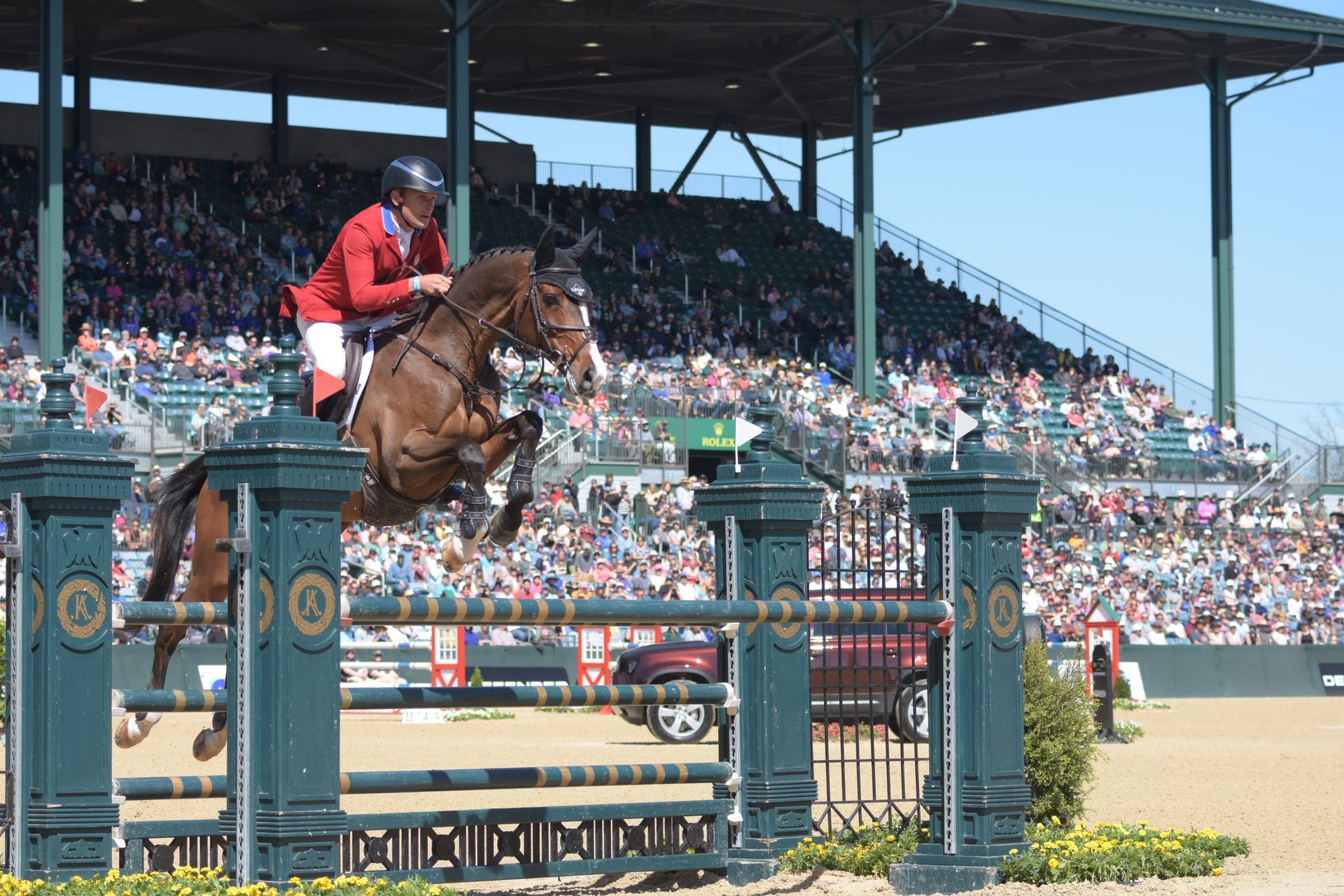A person is riding a horse over a hurdle at a horse show.