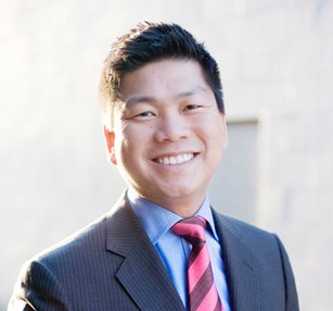 A man in a suit and tie is smiling for the camera