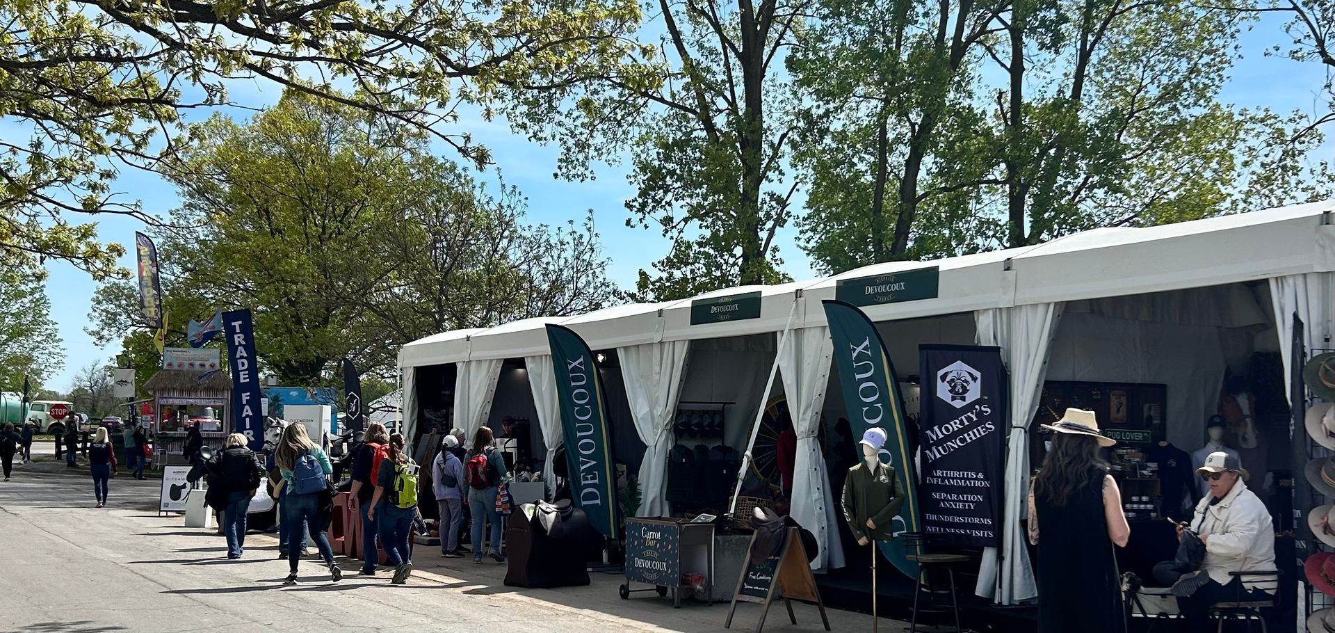 A group of people are standing in front of a row of tents.