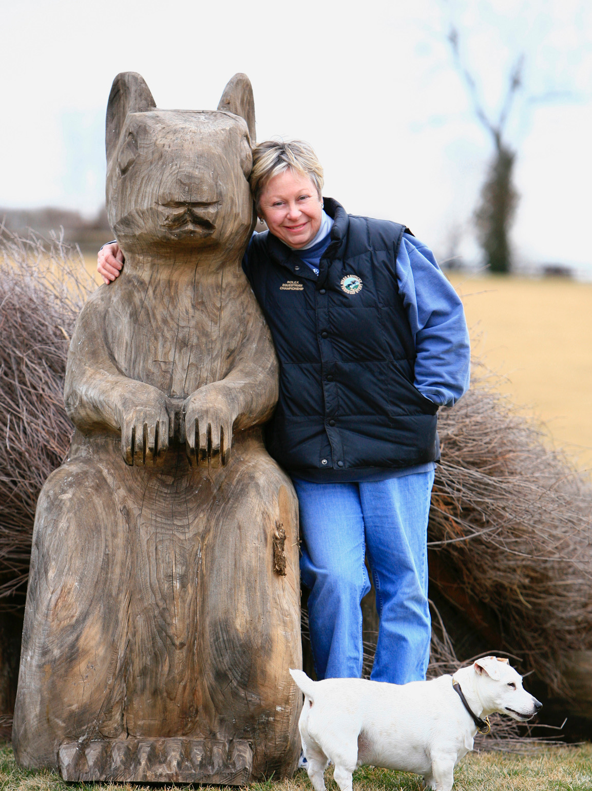 A woman standing next to a statue of a squirrel and a dog