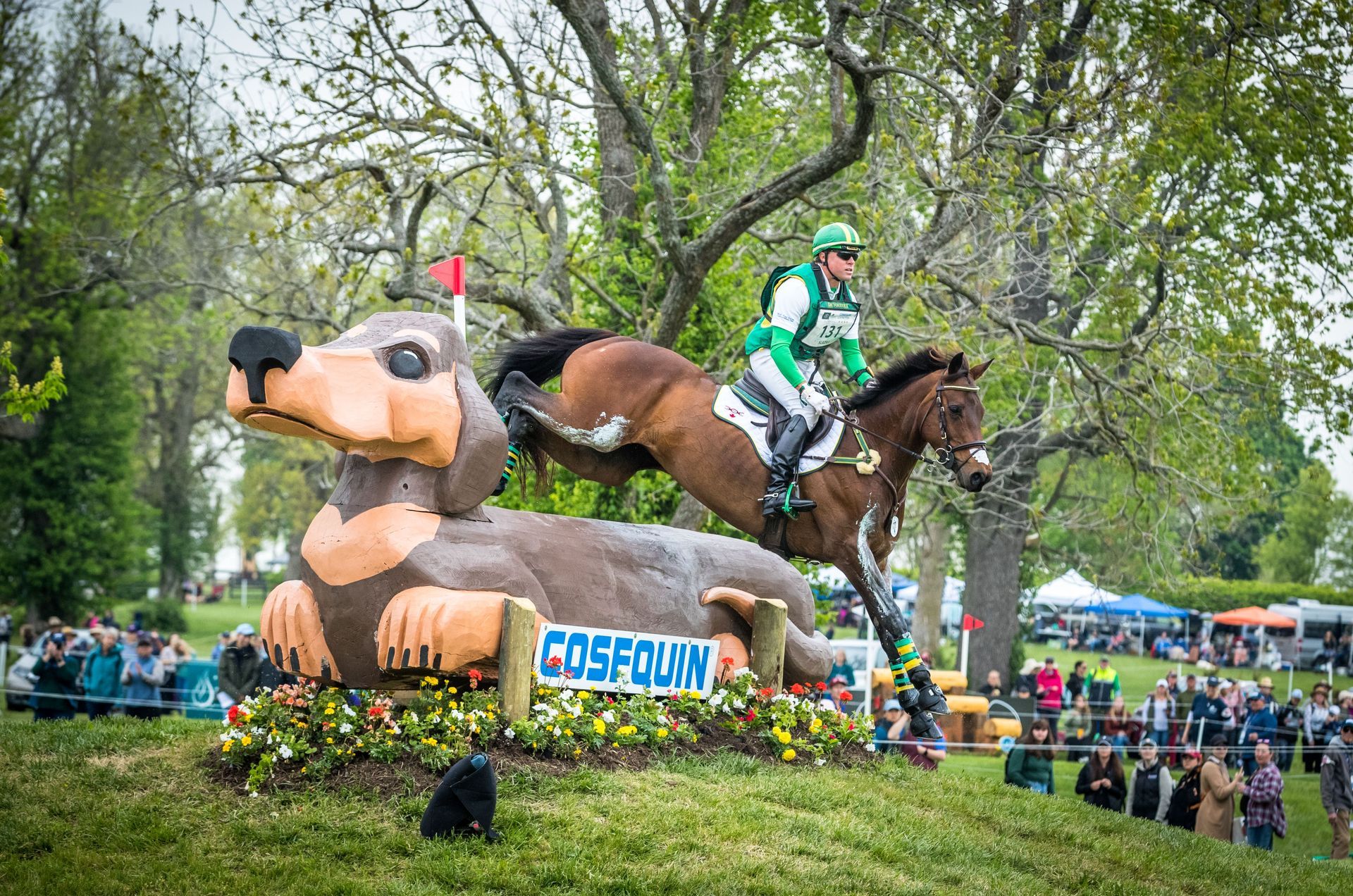A man is riding a horse next to a statue of a dachshund.