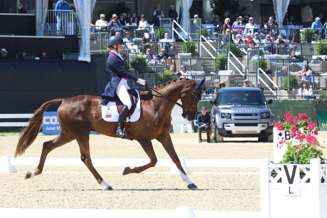 A woman is riding a brown horse on a dirt track.