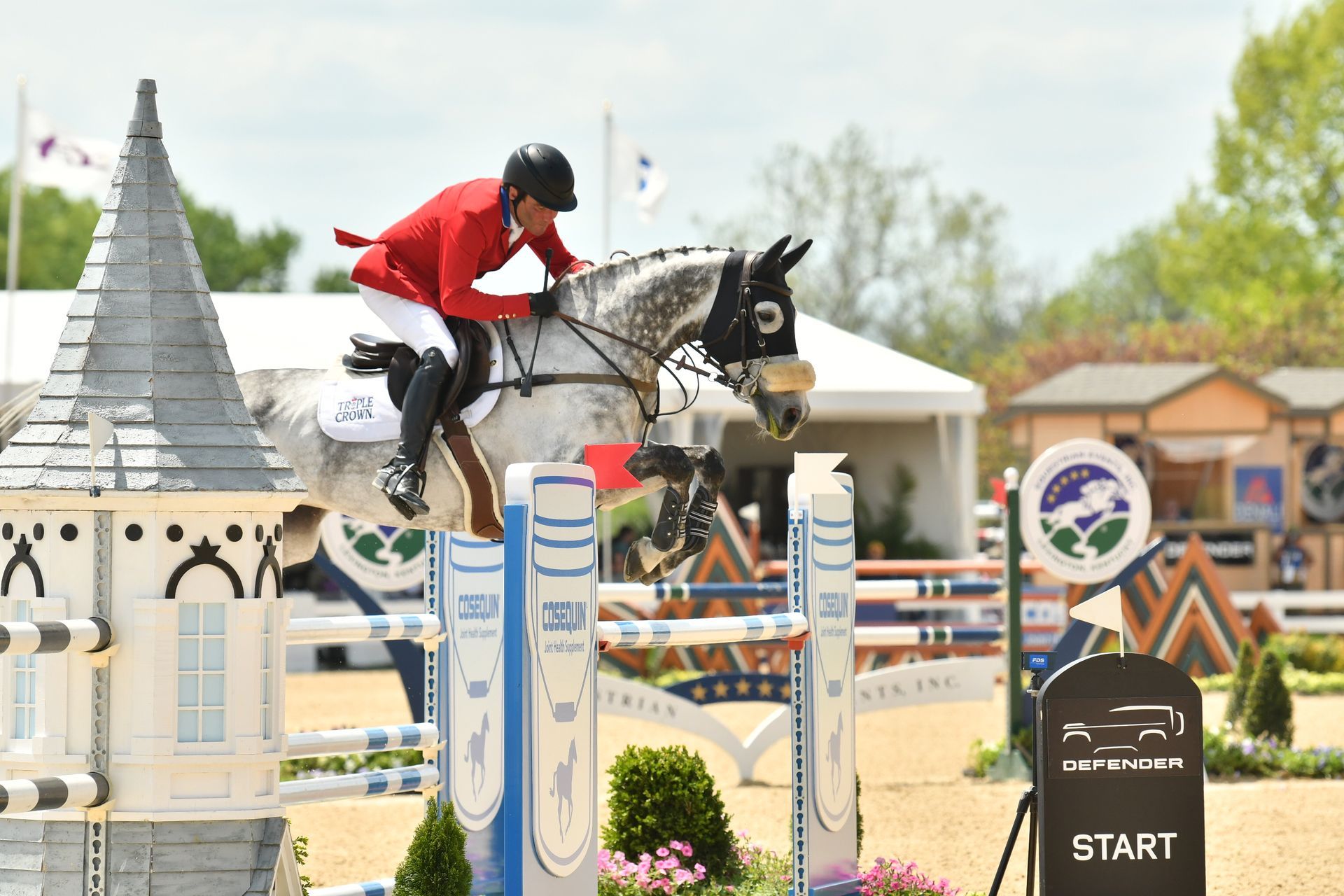 A man is riding a horse over a jump.