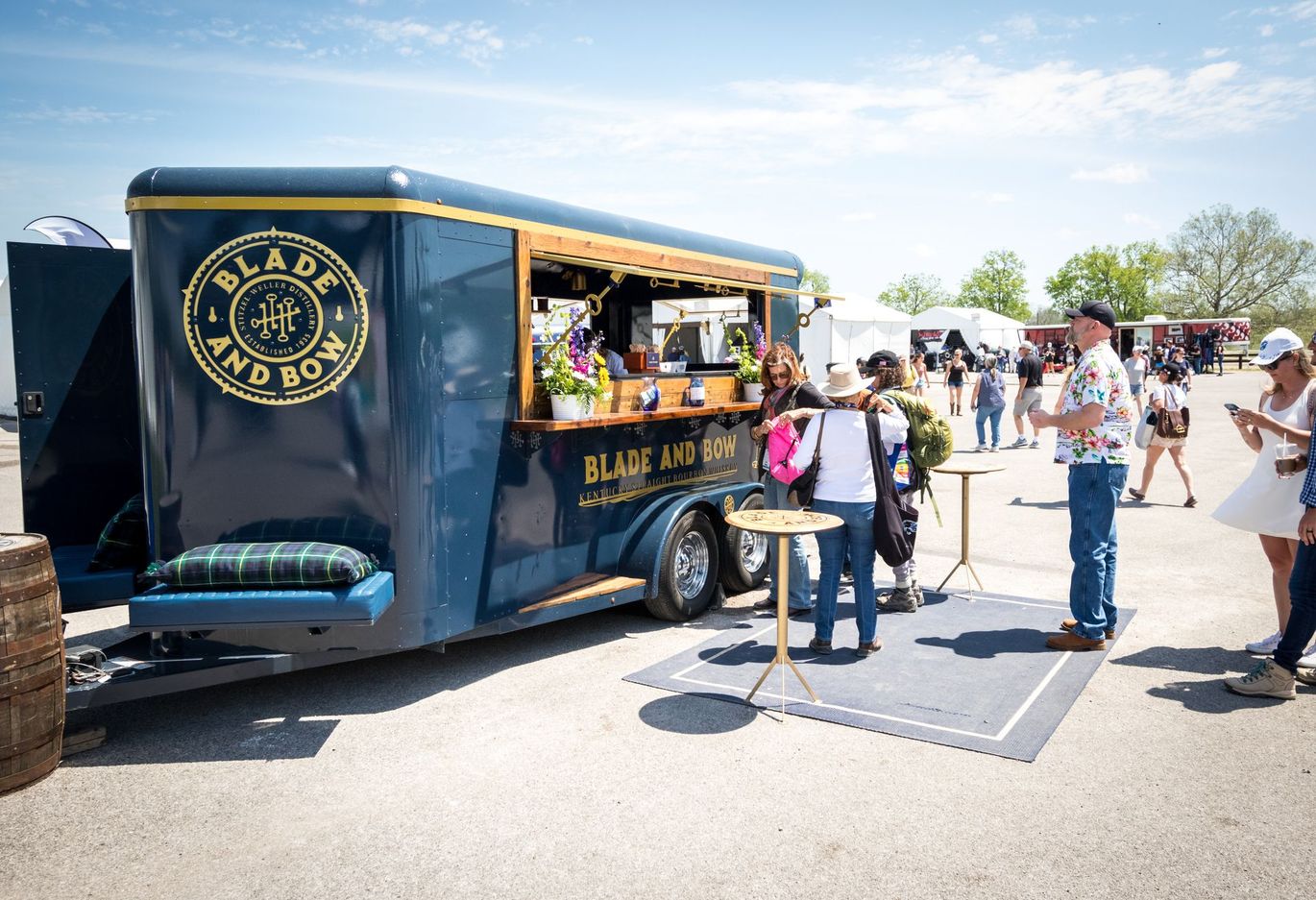 A food truck is parked in a parking lot with people standing around it.