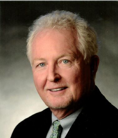 A man in a suit and tie is smiling for the camera.