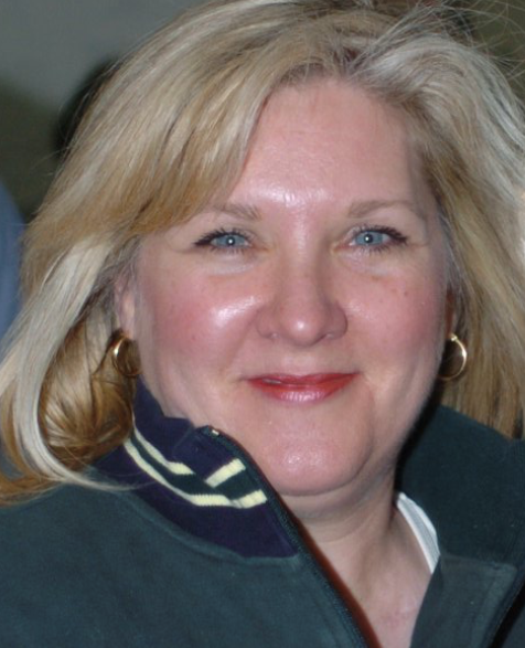 A woman with blonde hair and blue eyes smiles for the camera