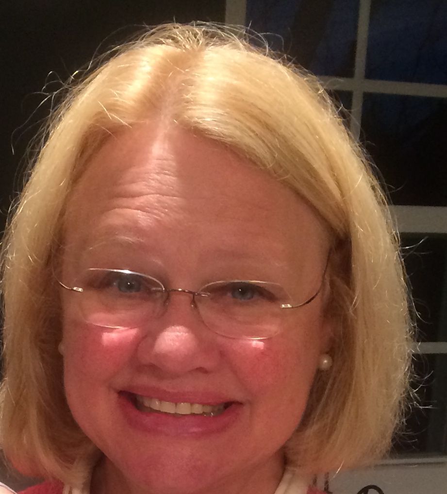 A woman with blonde hair and glasses smiles for the camera