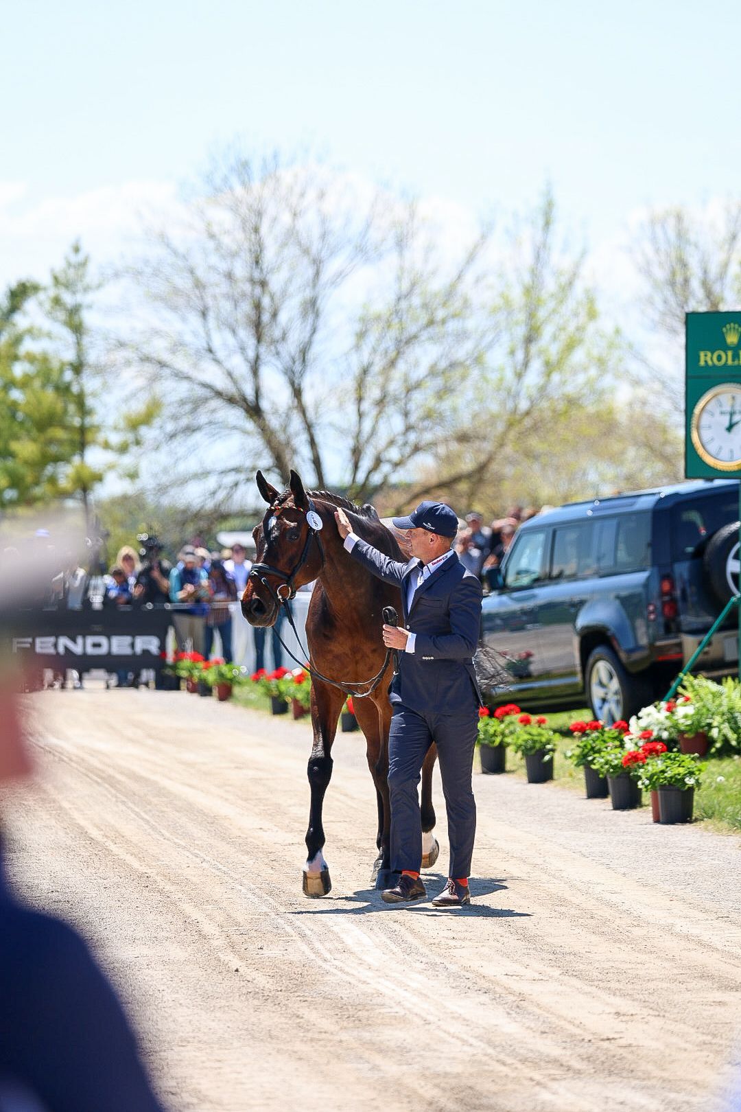 A man walks a horse in front of a crowd