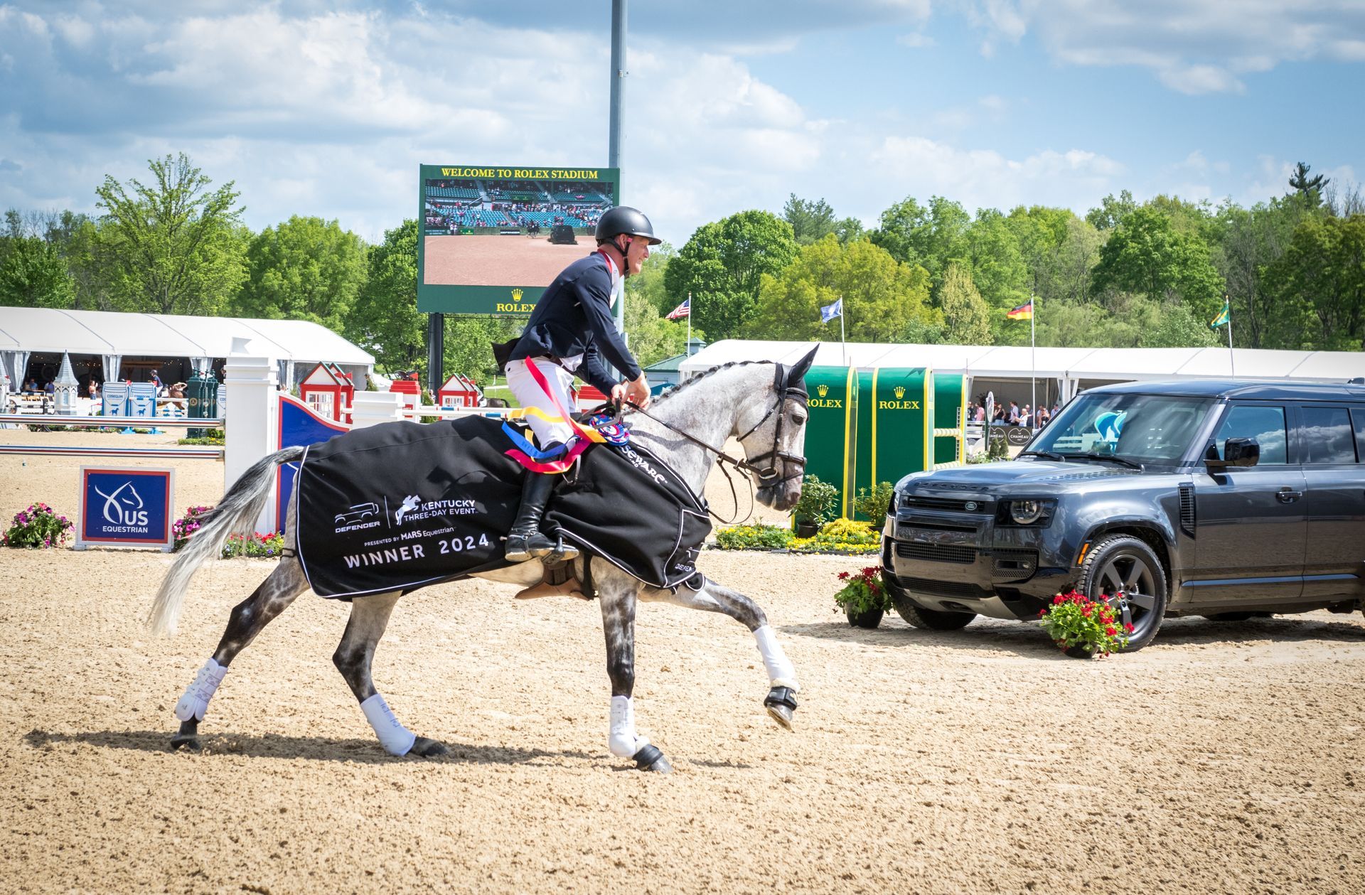 A man is riding a horse in front of a car.