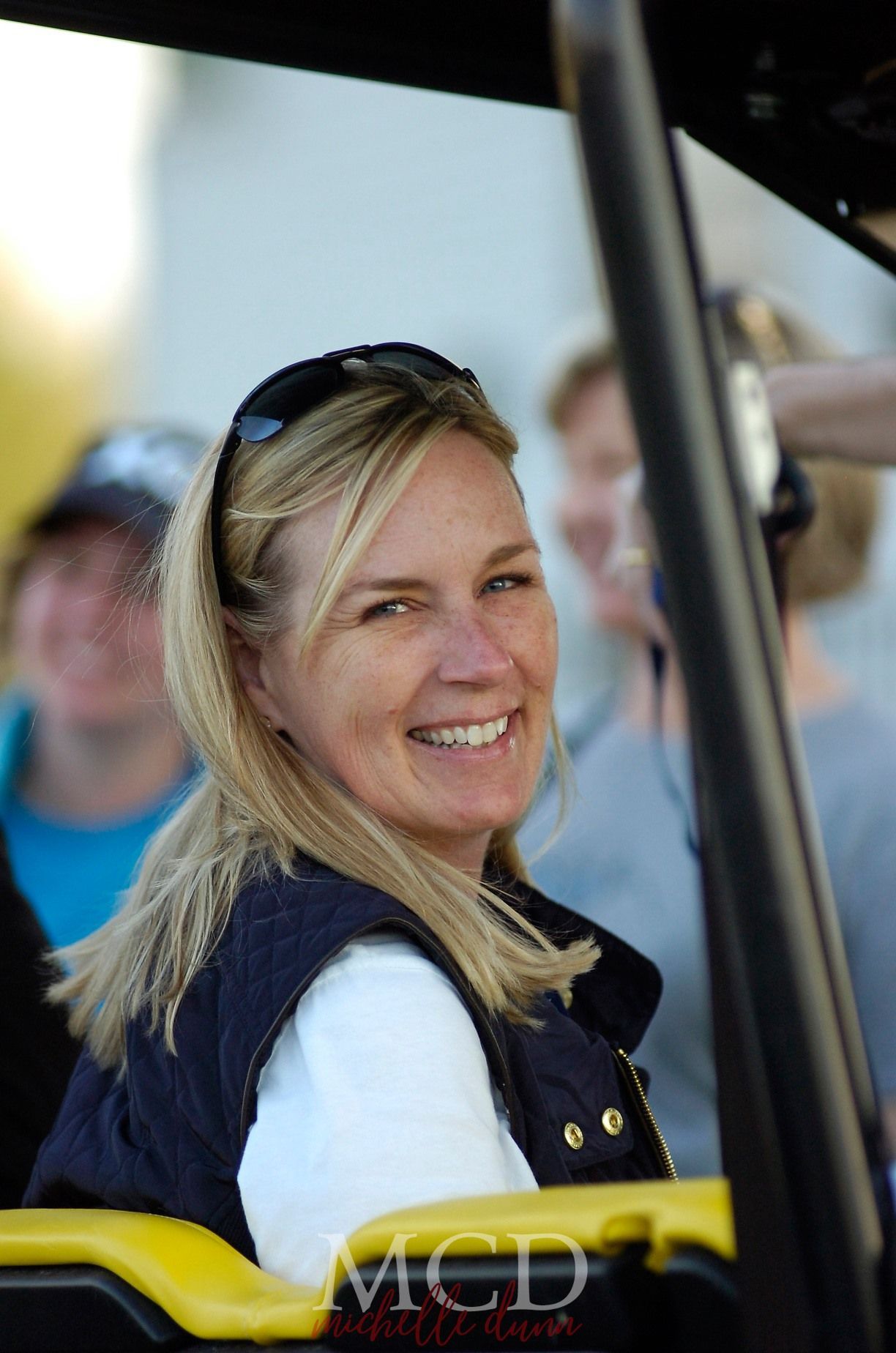 A woman is smiling while sitting in a vehicle that says mcd on it