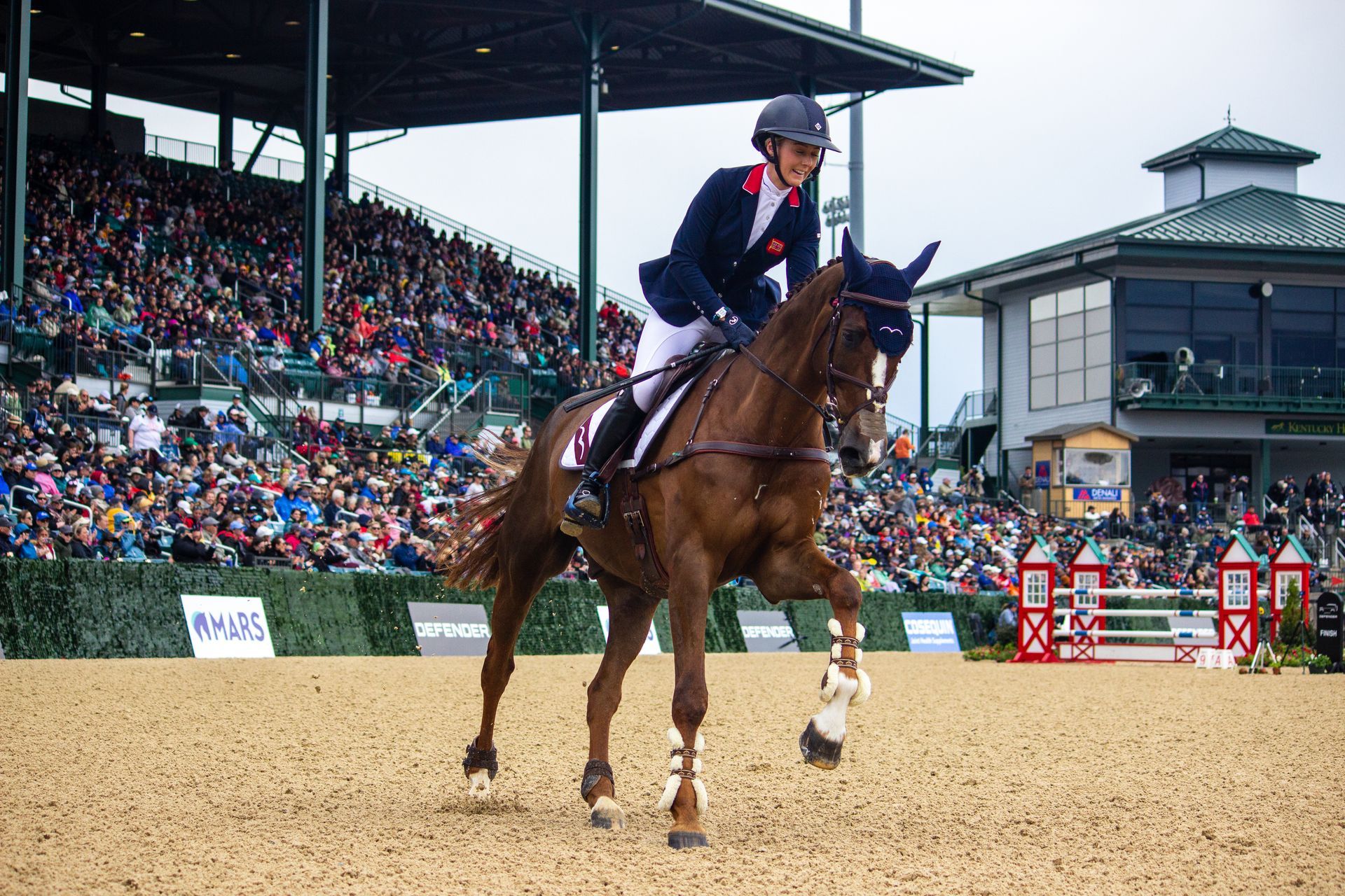 A woman is riding a horse in front of a crowd.