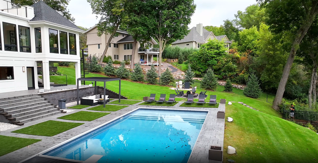 A patio with a table and chairs and an umbrella in front of a house.