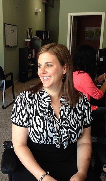 A woman is smiling while sitting in a chair in a room.