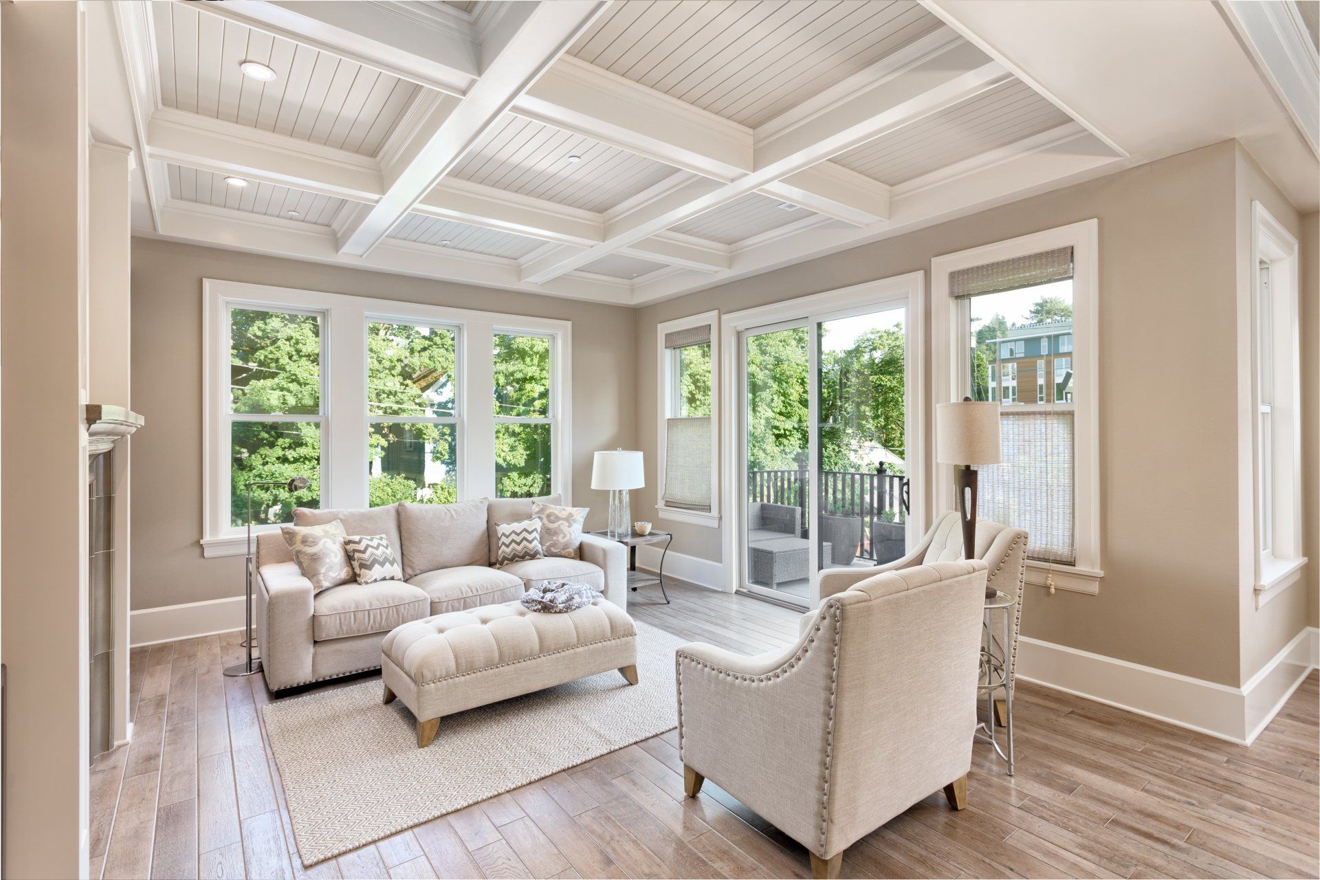 A living room with a couch , chairs , ottoman and sliding glass doors.