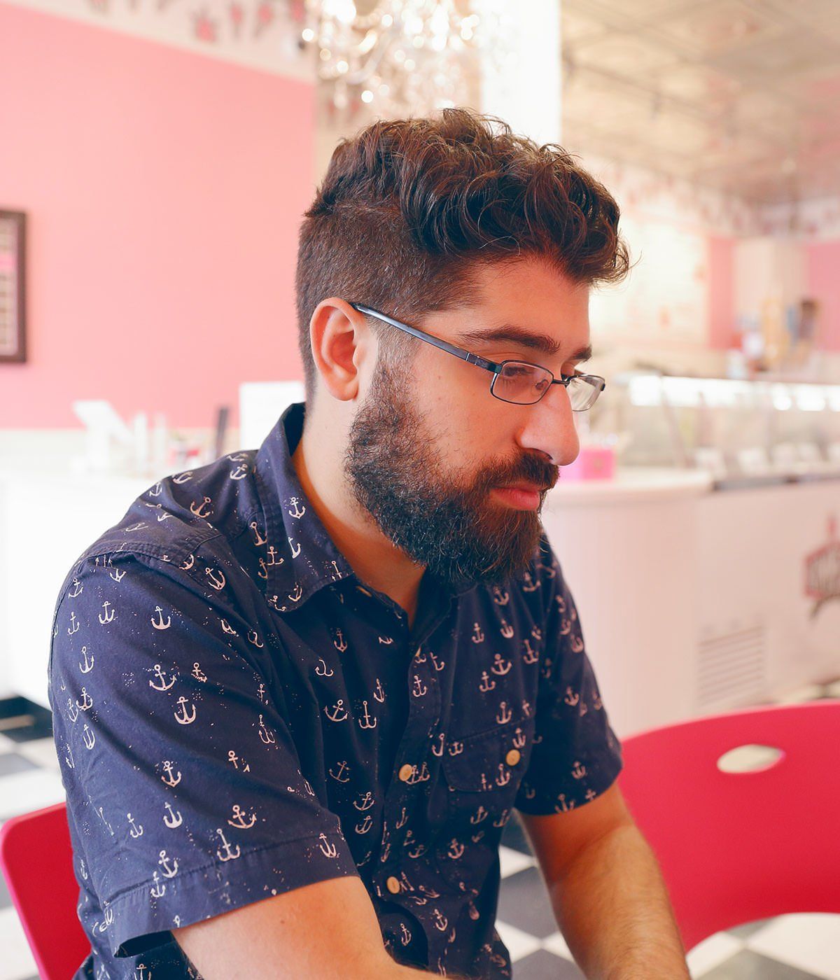 A man with a beard is wearing glasses and a blue shirt with anchors on it