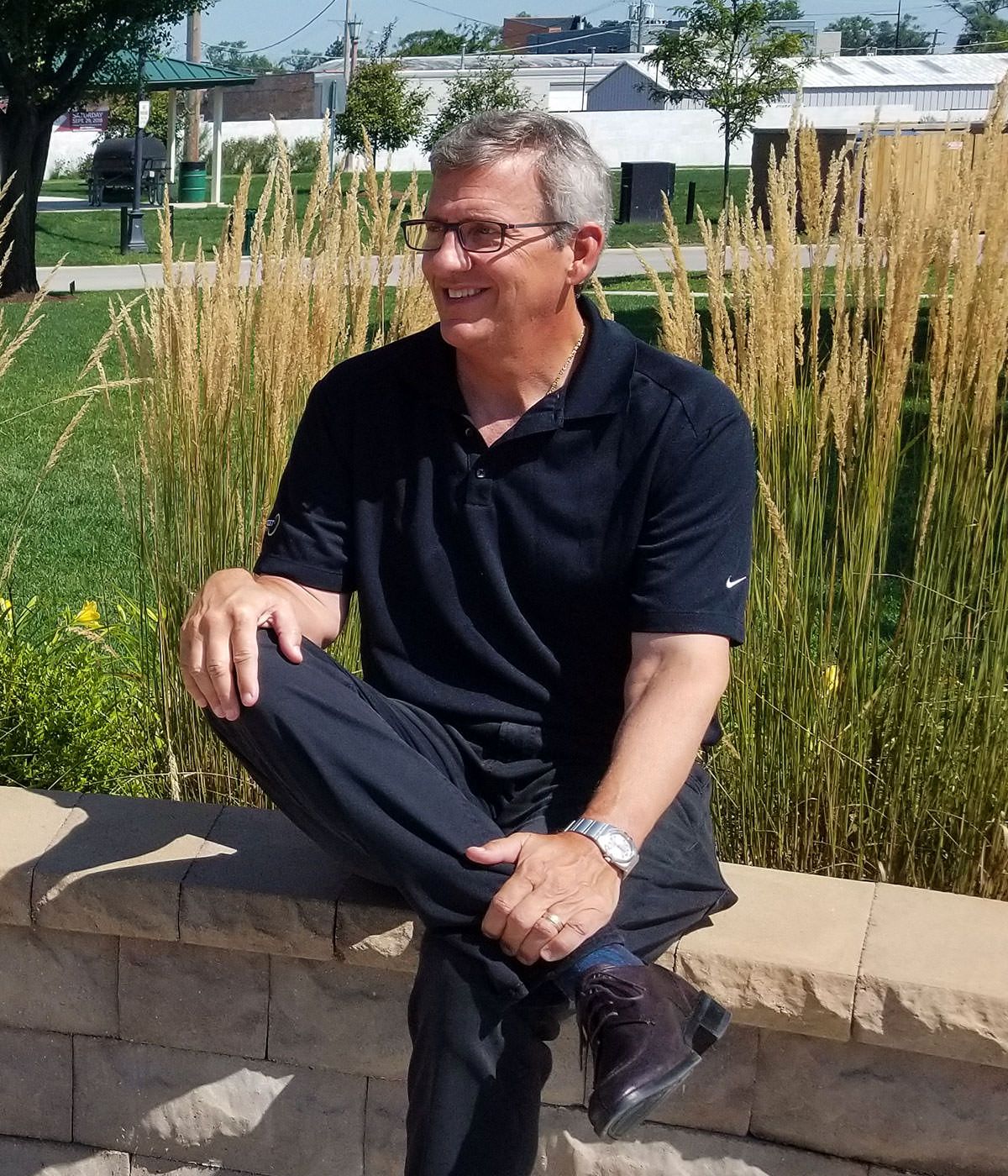 A man in a black shirt sits on a stone wall