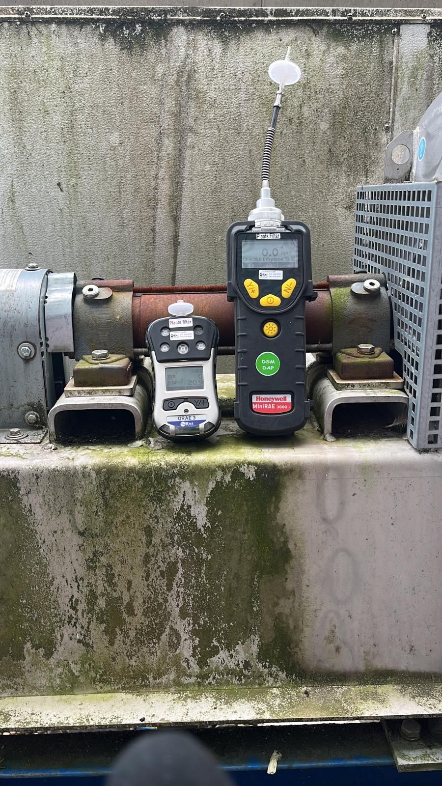 Twee gasdetectiemonitoren staan ​​op een metalen platform tegen een verweerde betonnen muur.