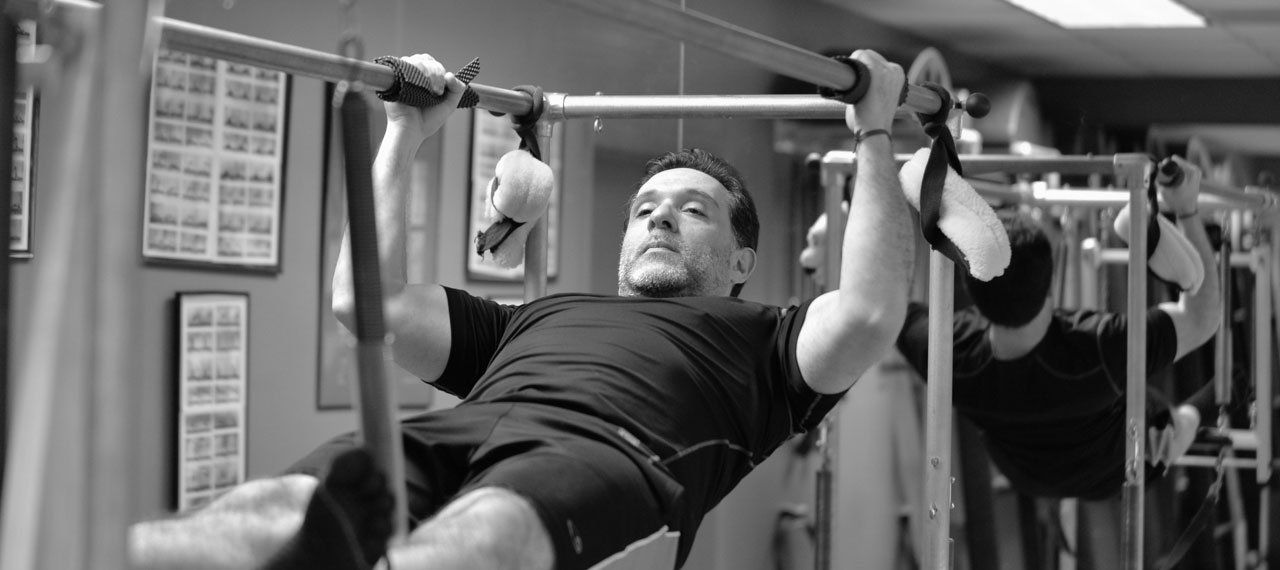 A man is doing pull ups on a Pilates Cadillac.