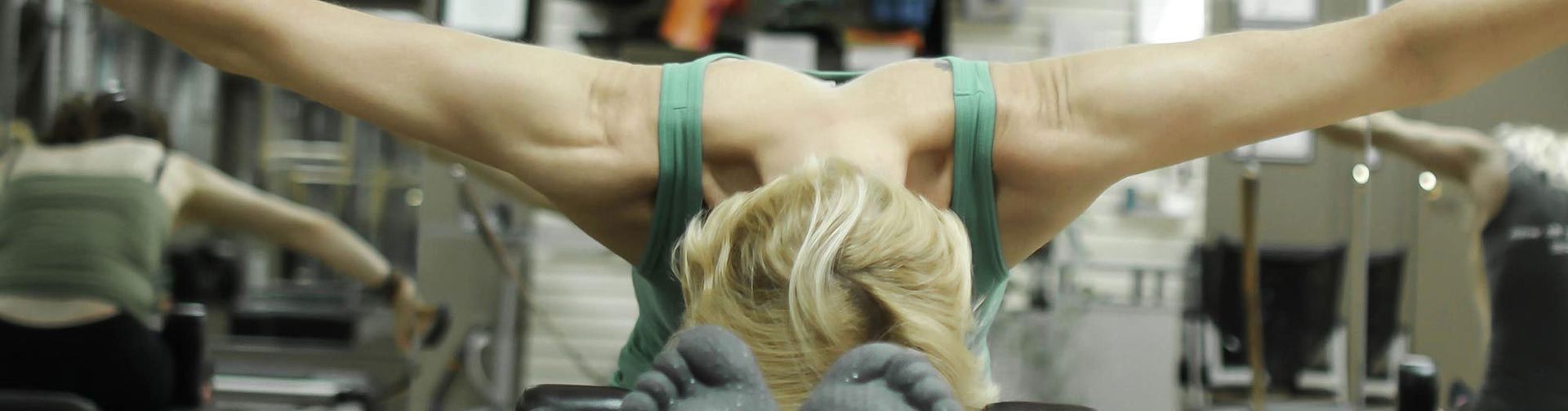 A woman is doing exercises on a Pilates machine in a studio.