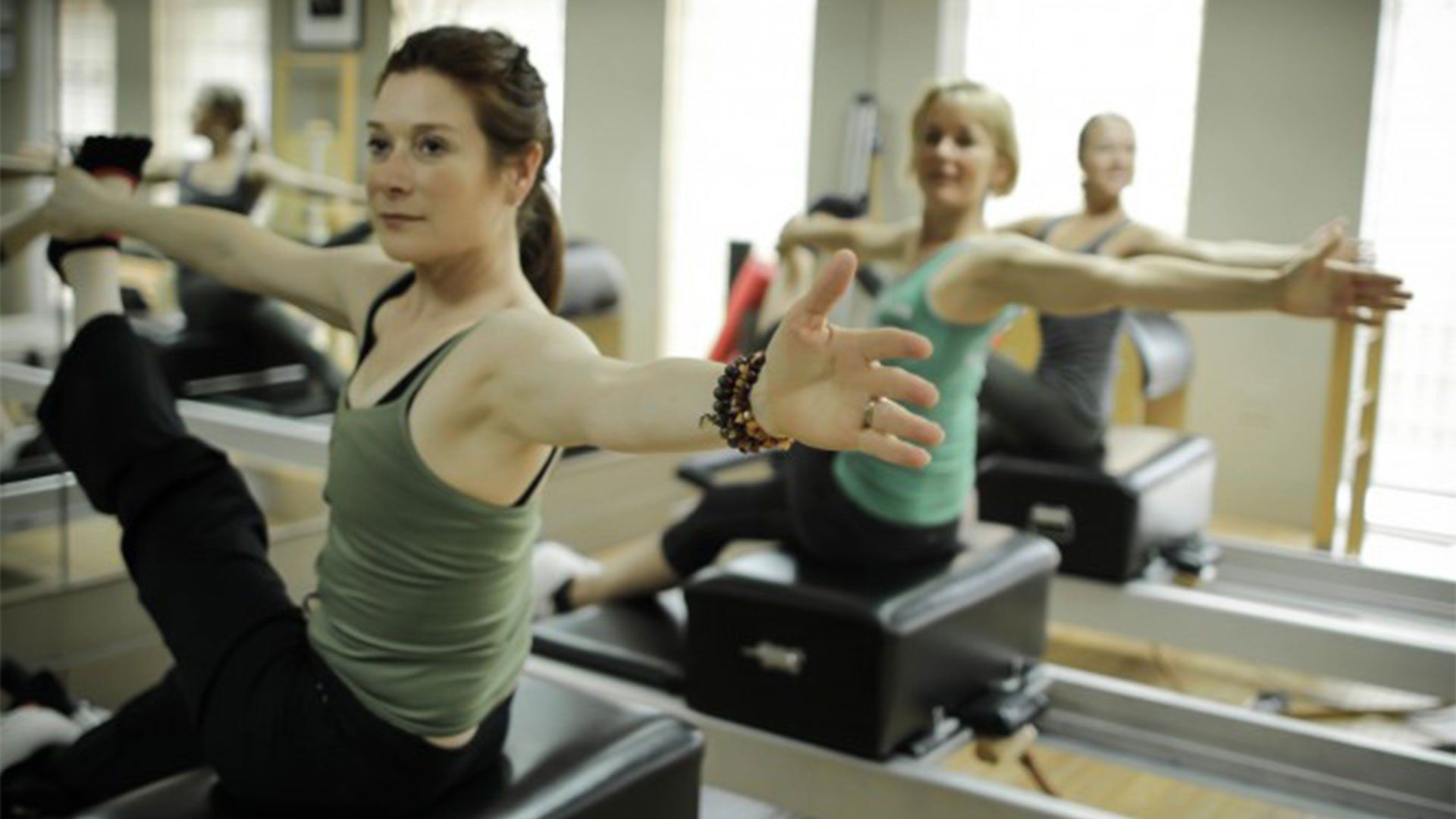 A group of women are doing pilates exercises in a studio.