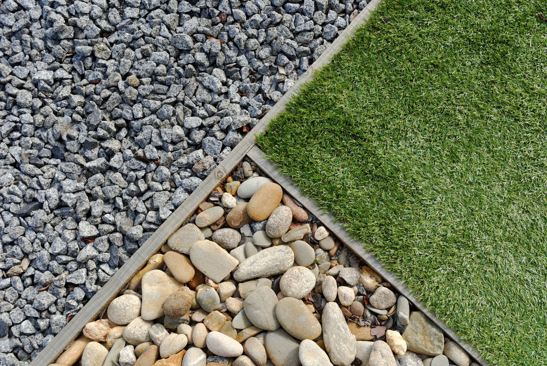 Gravel, pebbles, and artificial turf separated by concrete borders.