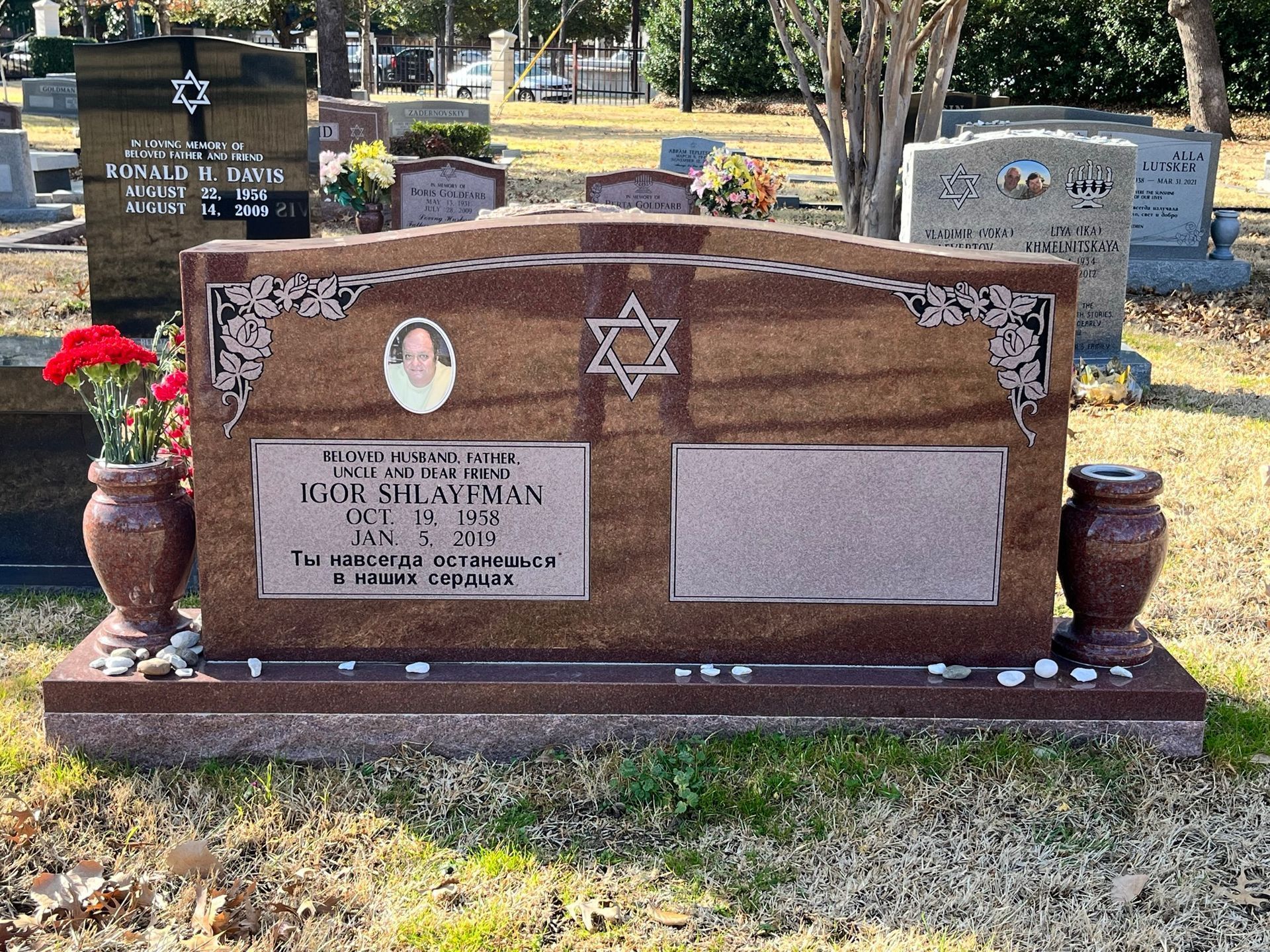 Headstone in a cemetery for Maria del Carmen Noriega, with a heart design and vases on each side.