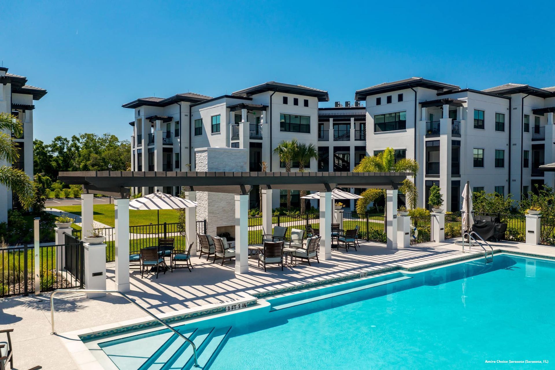 A large swimming pool in front of a large apartment building.
