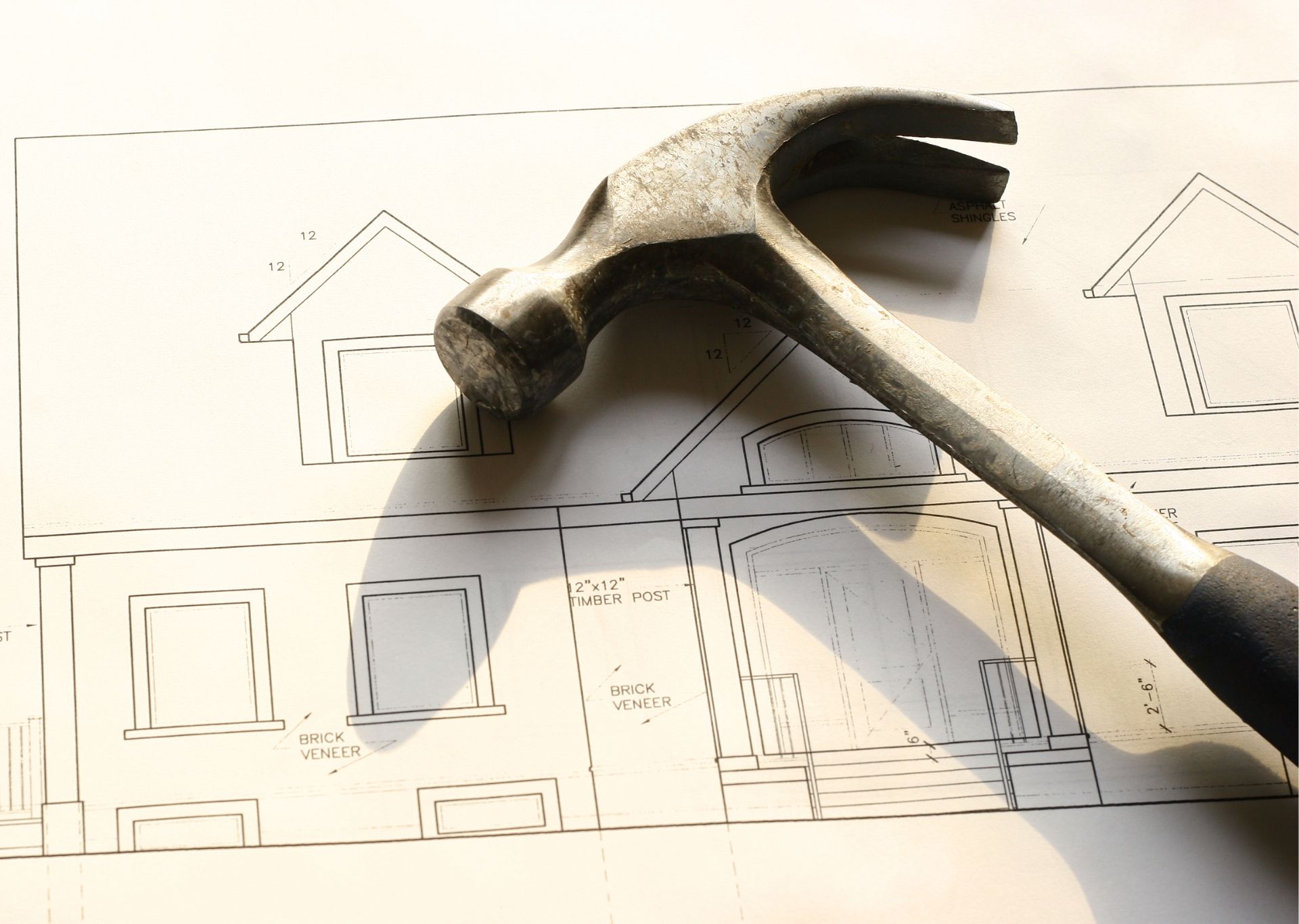Hammer on top of house blueprints.