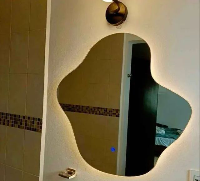 Elegante tocador de dormitorio con espejo con marco dorado, consola de mármol, taburete e iluminación cálida.