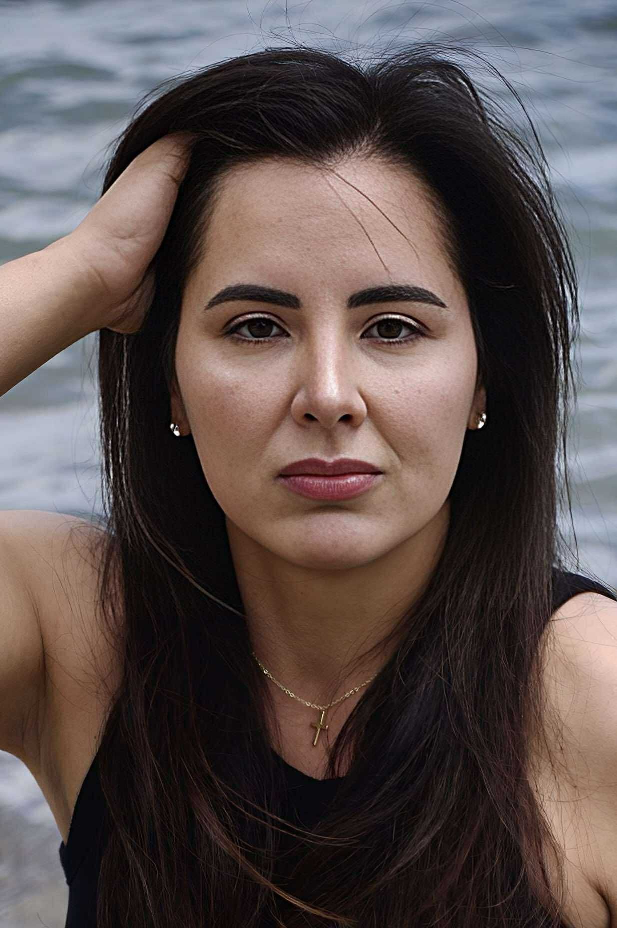 A woman with her eyes closed is touching her face with her hand.