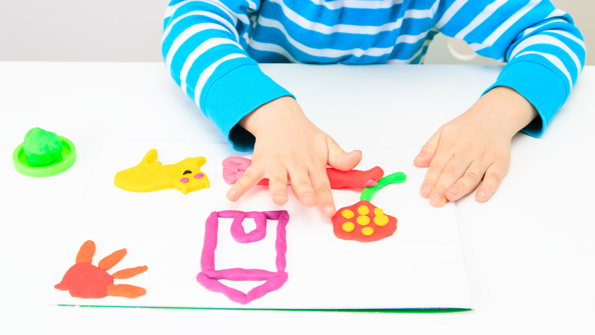 A child is playing with play dough at a table.