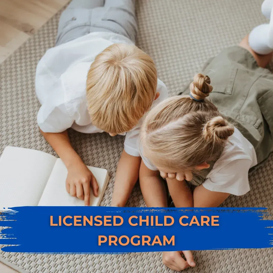A boy and a girl are laying on the floor looking at a book ..