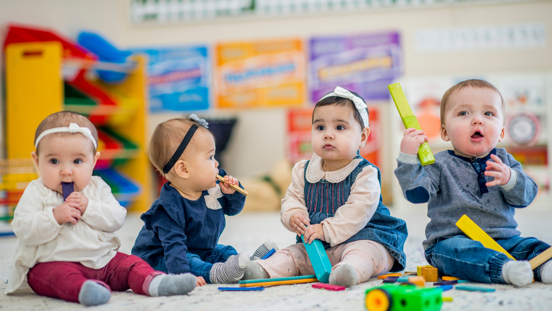 A group of babies are sitting on the floor playing with toys.
