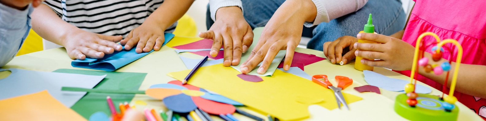 A group of children are sitting at a table making crafts.