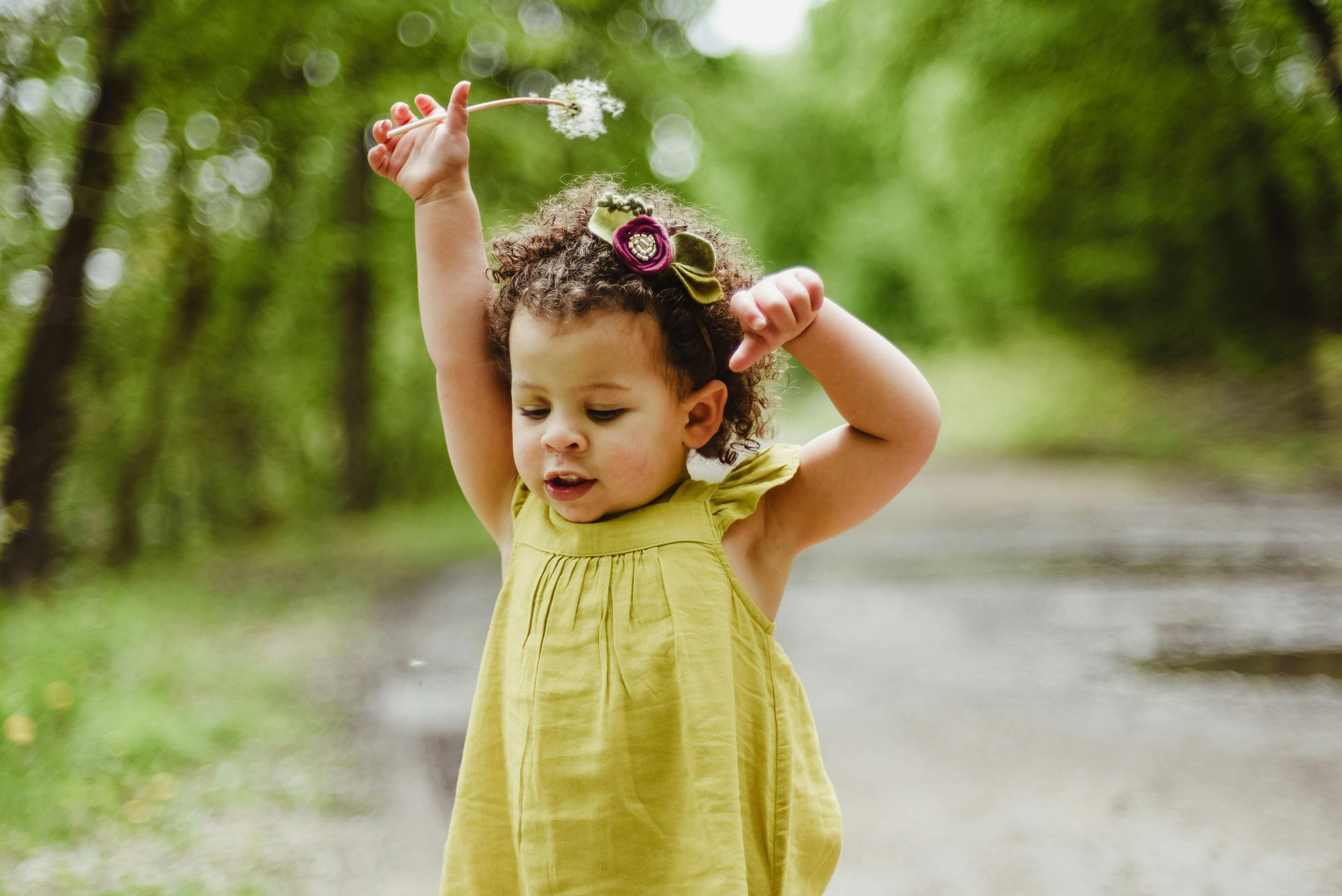 A little girl in a white shirt is holding a piece of bread.