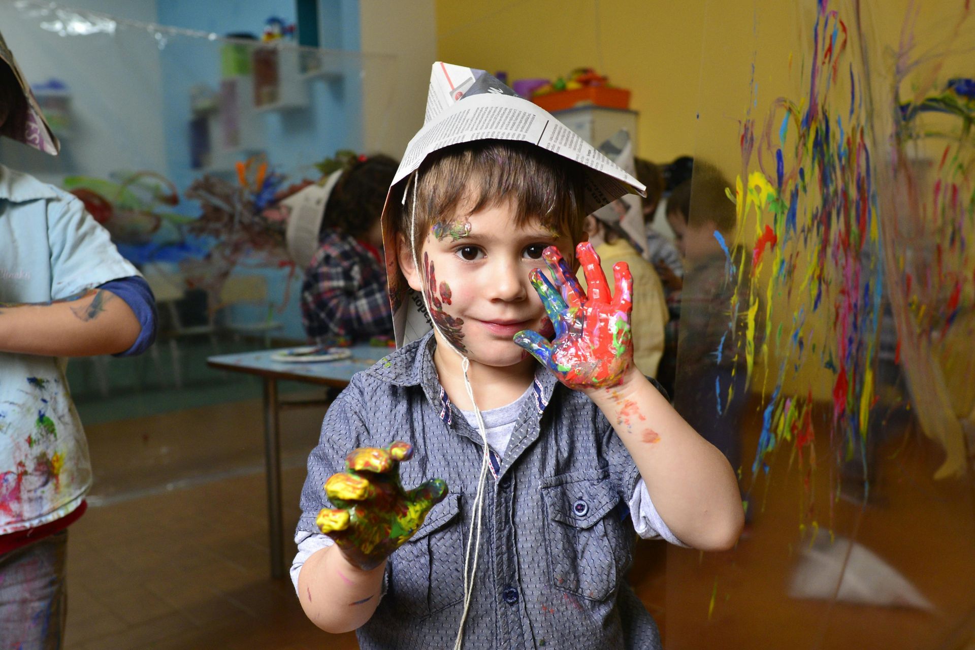 A young boy with his hands covered in paint.