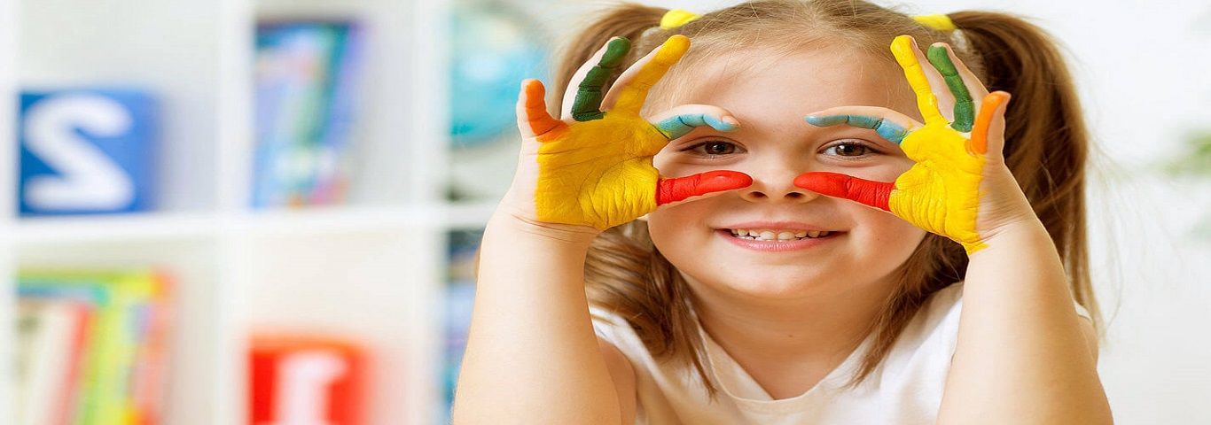 A little girl with paint on her face is making a funny face.