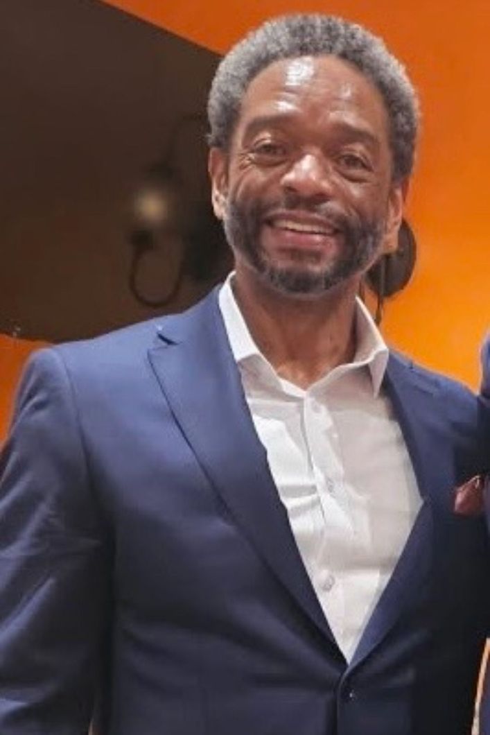 A man in a blue suit and white shirt is smiling for the camera.