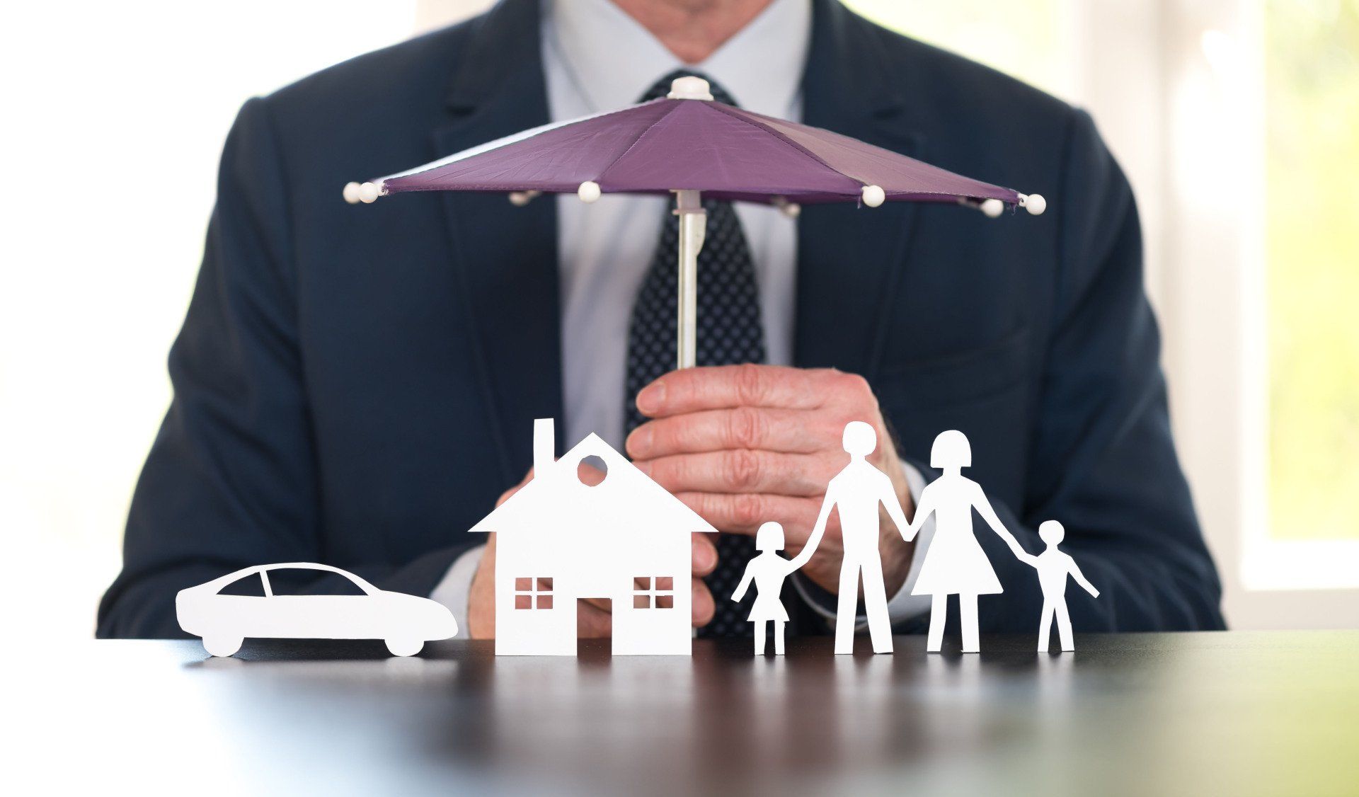 man in suit holding umbrella over family