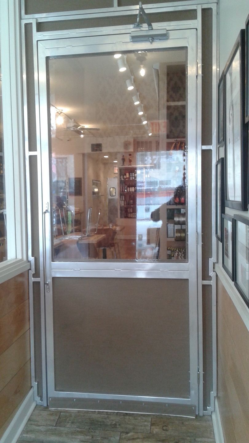 A hallway with a glass door leading into a room.