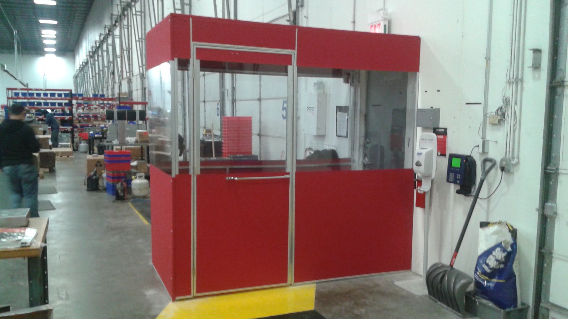 A red room with a glass door in a warehouse.