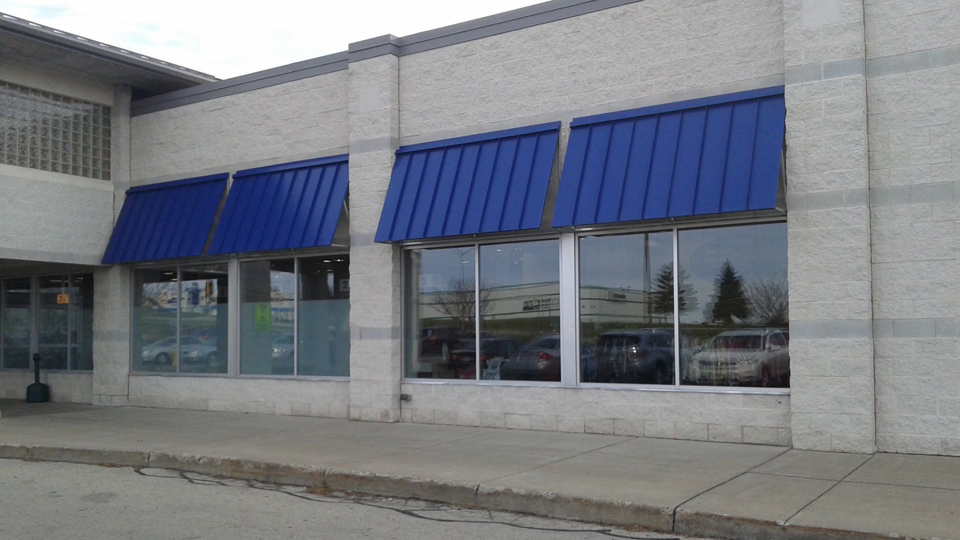 A brick building with blue awnings on the windows.