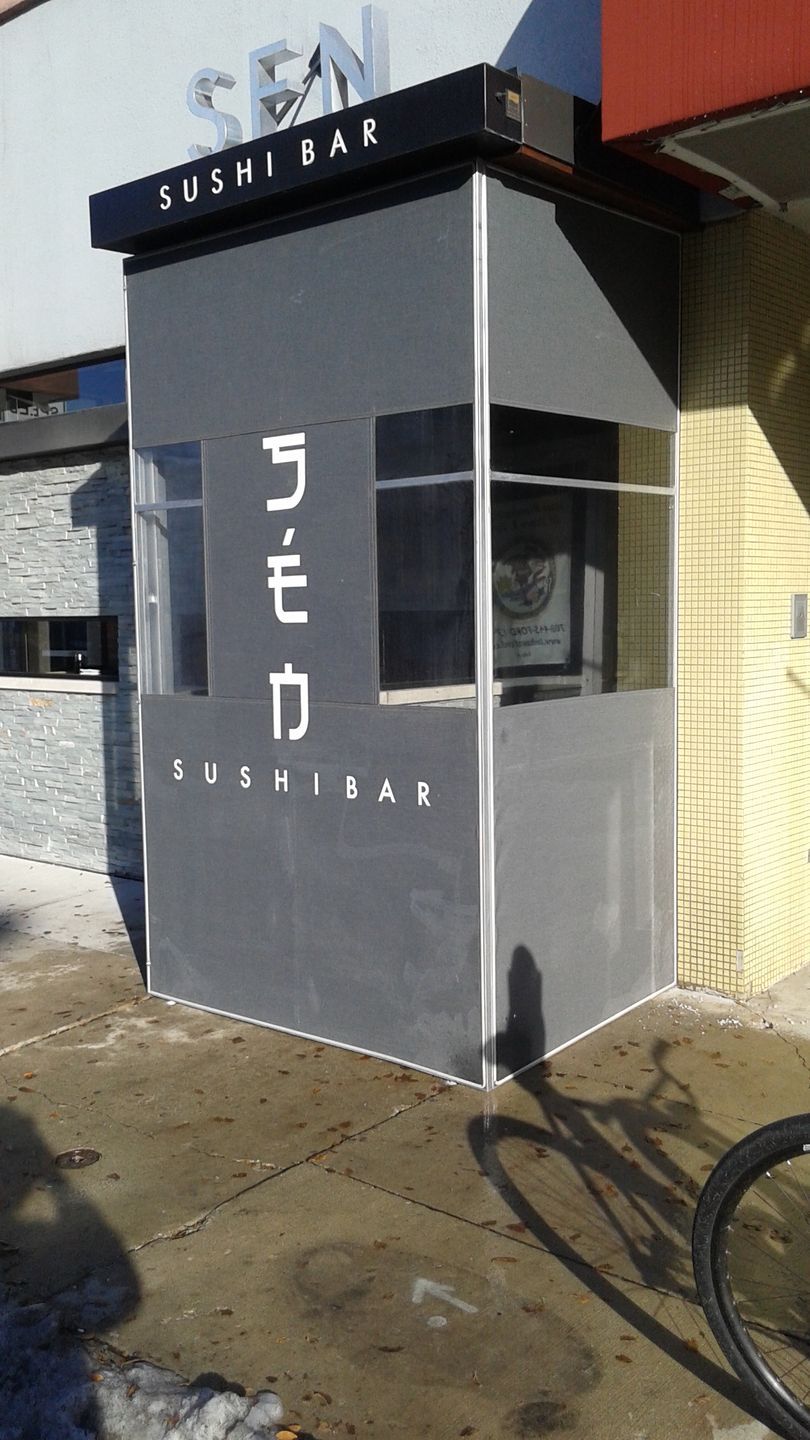 A bicycle is parked in front of a sushi bar.