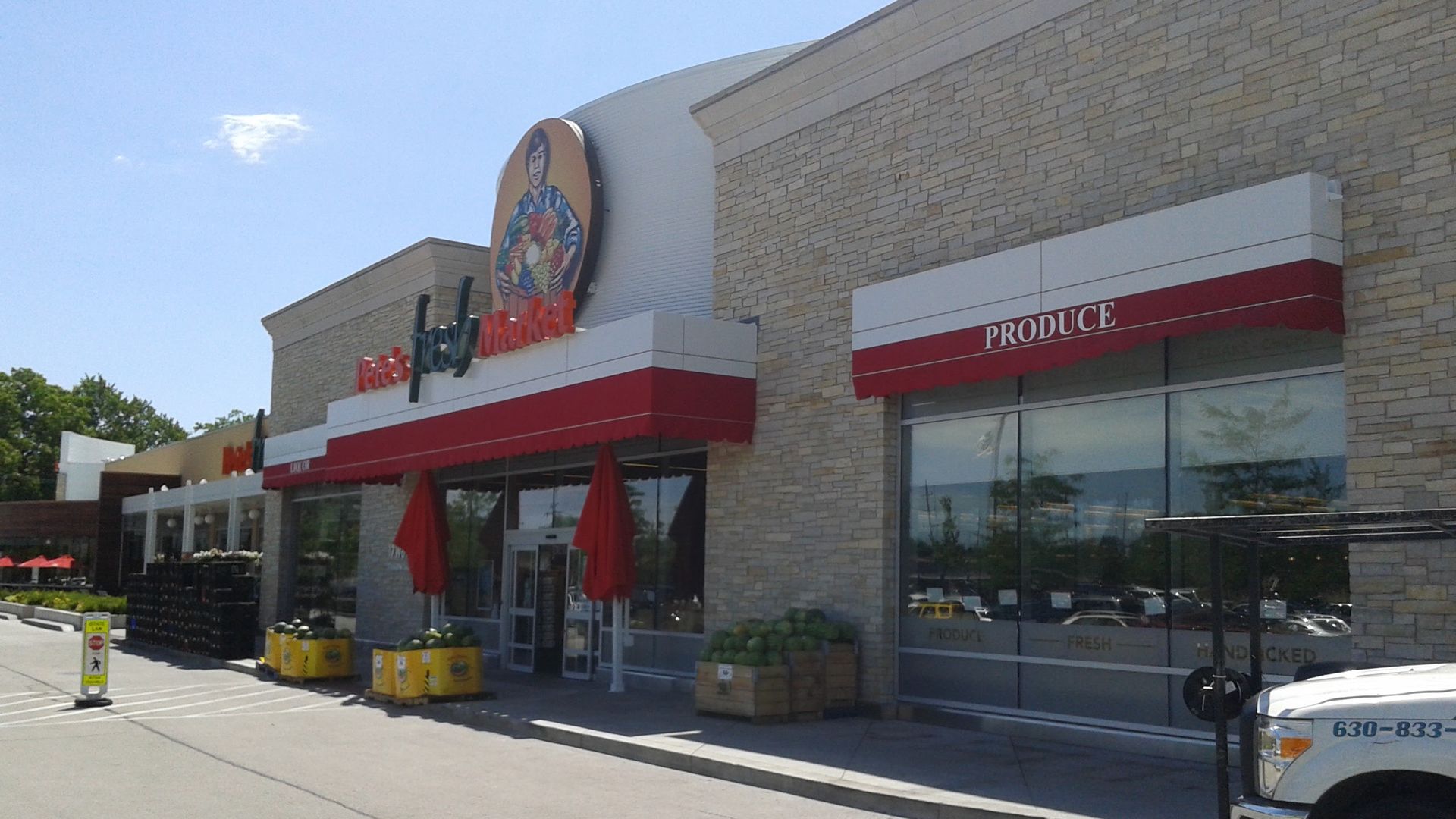 A white truck is parked in front of a grocery store