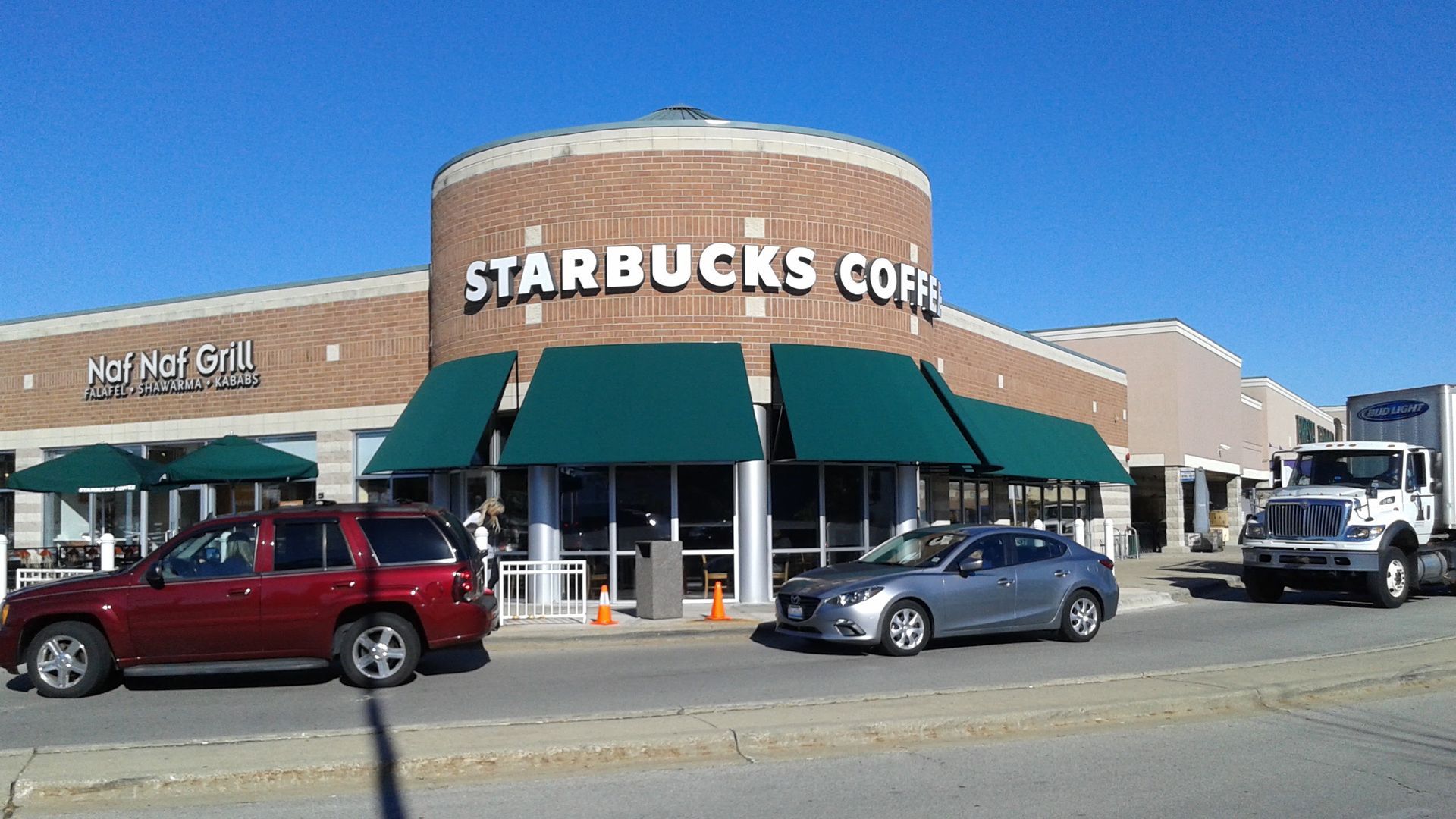 Cars are parked in front of a starbucks coffee shop