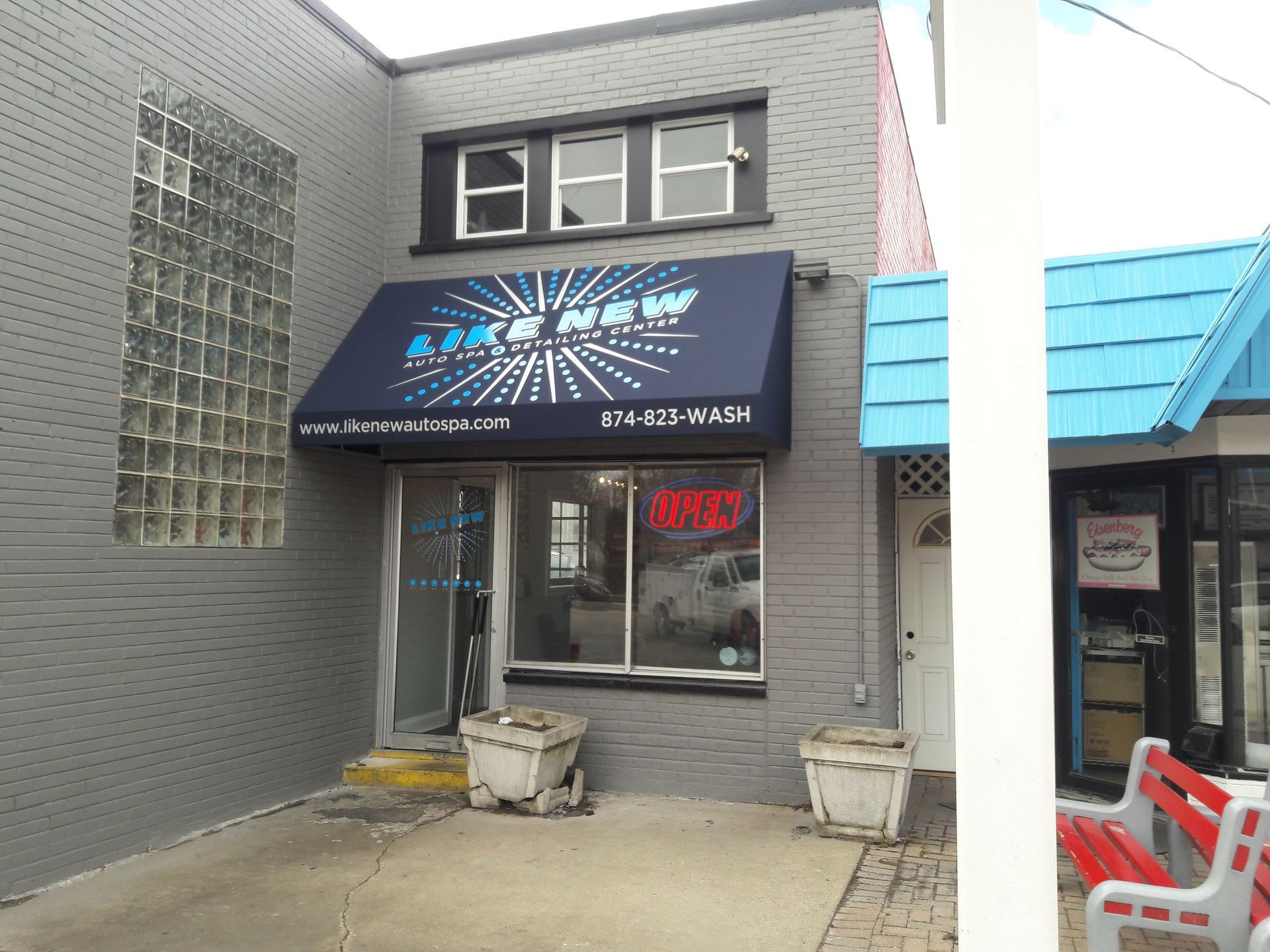 A store front with a blue awning and an open sign