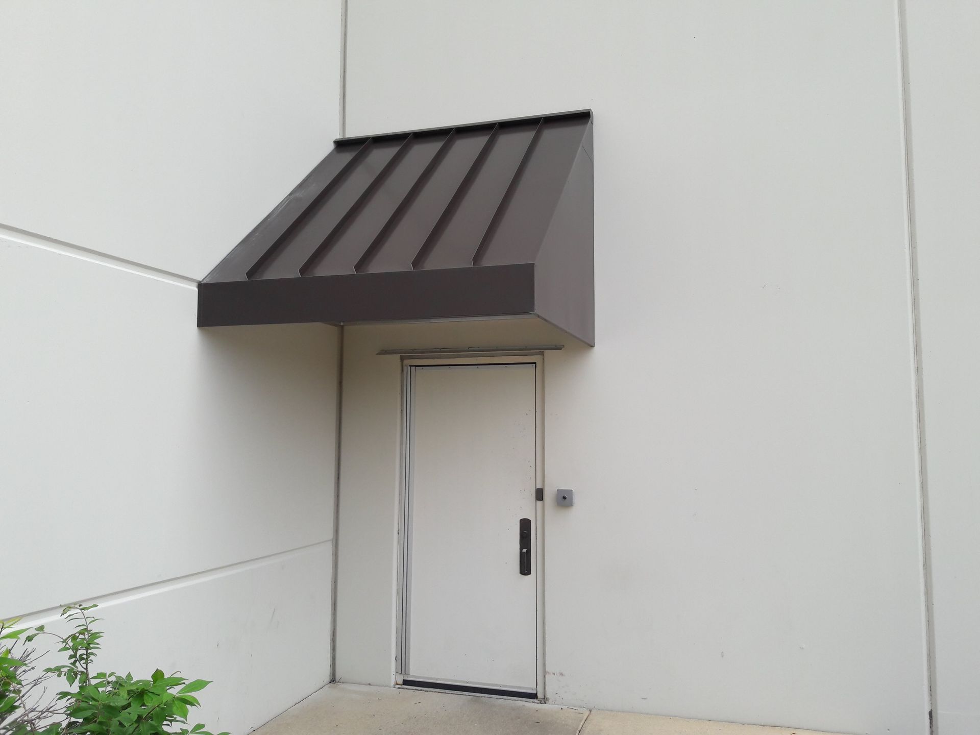 A white door with a brown awning over it