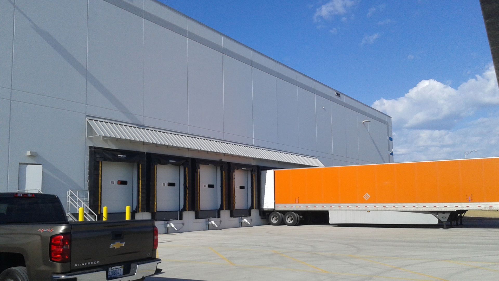 A truck is parked in front of a warehouse loading dock.