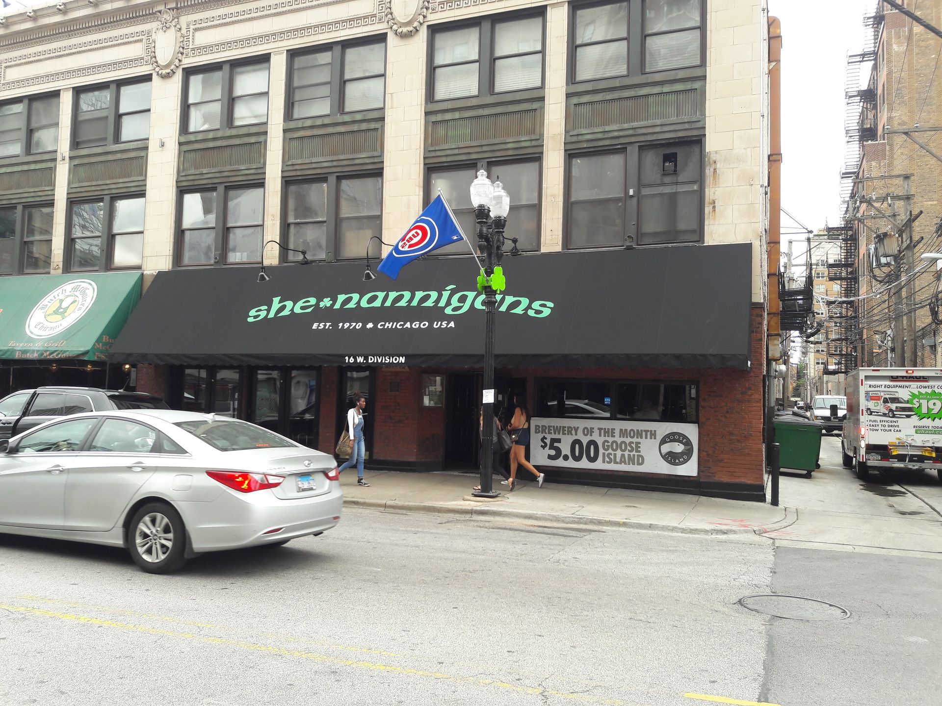A car is parked in front of a building that says the nanniline